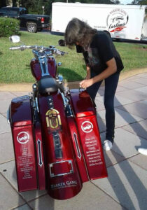 Foreigner's Kelly Hansen signing Shriners Childrens' motorcycle at hospital
